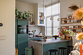 Kitchen with green cabinets, concrete worktop and plants