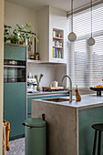 Kitchen with green cupboards, concrete worktop and white tiled backsplash