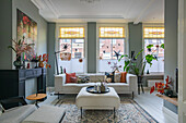 Bright living room with white furniture and large windows with stained glass