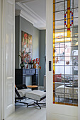 Living room with designer armchair, mantelpiece and ornate stained glass window