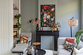 Living room with light grey walls, black mantelpiece and flower painting