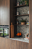 Kitchen with niche shelving, marble wall and fresh oranges on counter