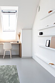 Bright study with skylight, minimalist desk and white wall shelves