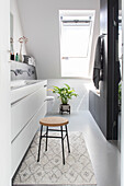 Modern bathroom with skylight, white washbasin and stool on a patterned carpet