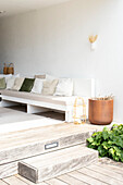 White lounge bench with green and white cushions on wooden terrace