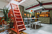 Retro kitchen with green cupboards and coral red staircase to the skylight