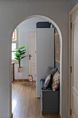 Passageway to a bright, modern room with plants and bench seat