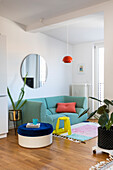 Living area with turquoise sofa, round mirror and colourful decoration