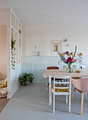 Dining area with wooden and metal chairs, mint-colored wood paneling and light partition wall