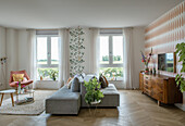 Bright living room with light grey sofa, wooden sideboards and plants