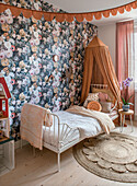 Children's room with floral patterned wallpaper and canopy over the bed