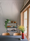 Arched room with metal wall, shelf and yellow flowers in a red vase