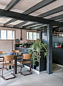 Dining area with wooden table and chairs in modern kitchen with black furnishings