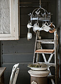 Vintage corner on terrace with ladder and hanging kitchen utensils