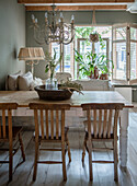 Dining room with rustic wooden table, vintage chairs and chandelier