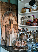 Rustic kitchen corner with wooden chopping boards and wire basket with eggs