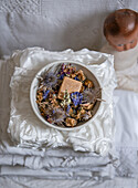 Bowl with dried flowers and bar of soap on a folded pile of fabric