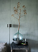 Decorative branch in large glass vase on rustic side table