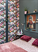 Bedroom with floral wallpaper, shelf and artwork on green wall