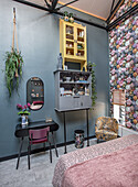 Bedroom with floral pattern wallpaper, table and cupboards with decorations