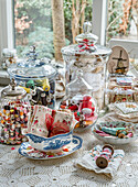 Vintage-look sewing utensils with spools of thread and fabrics in glass containers on crochet blanket