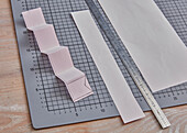 DIY project with pink paper strips, ruler and cutting mat