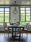 Dining area with antique wooden table, shabby chic chairs and fresh cut flowers