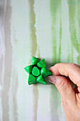 DIY decoration made from green modeling clay in the shape of a star on a striped background