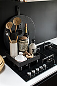 Kitchen utensils and oil bottles on a black gas hob