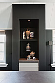 Built-in shelving in black with decorative ceramic vases and lighting