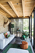 Living room with light-coloured wooden ceiling, brick wall and green accents