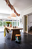 Wooden table with modern chairs, white pendant lights and fringed garland in the dining room