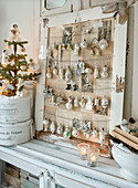 Antique Christmas tree decorations hanging in a window frame lined with old newspaper, Christmas tree in front of it