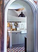 View through an open arched door into the kitchen