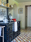 Country kitchen with black oven and antique floor tiles