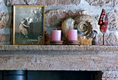 Candles, old photo and snail shell on stone fireplace mantelpiece