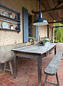Covered, rustic veranda with table and wooden benches