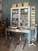 Display cabinet with crockery on table and vintage chairs