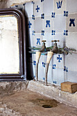 Old stone washbasin with vintage tap in front of wall tiles