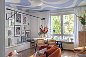 Living room with wall art, patterned ceiling and view of the greenery