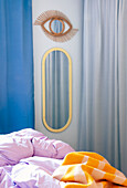 Mirror with oval frame and eye-shaped mirror above bed with colorful bed linen