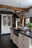 Kitchen with exposed wooden beams and white cupboards