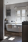 Bathroom with free-standing bathtub and white shutters