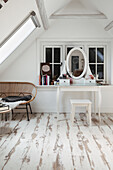 Attic bedroom with dressing table, rattan bench and wooden floorboards