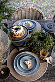 Laid garden table with Christmas cake, crockery and natural decorations