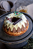 Festive bundt cake with chocolate icing and Christmas decorations on an antique cake platter