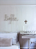 Bedroom with white wood paneling, neon lettering liefde and candlestick