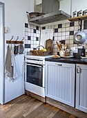 Small kitchen with white cupboard doors, wooden floor and tiled backsplash in black and white pattern