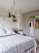 Bedroom with double bed and crocheted bedspread, white chandelier and shelves