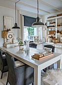 Dining room with white wooden furniture, black rattan chairs and hanging lamps